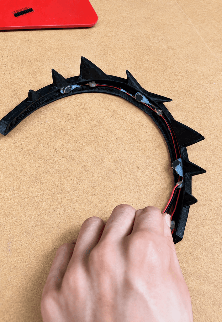 A hand testing a black headband fitted with a row of haptic modules.