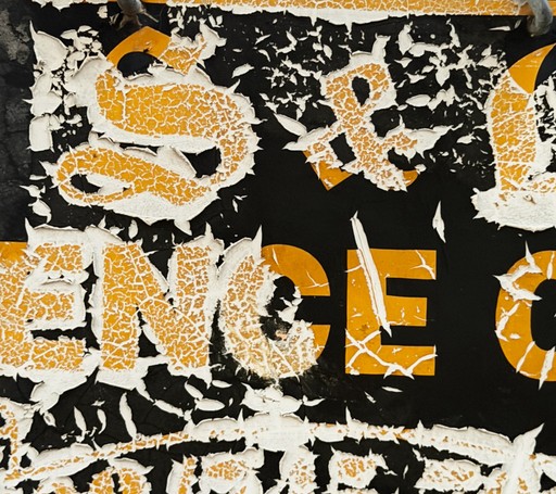 Weathered gold lettering on a torn black surface.