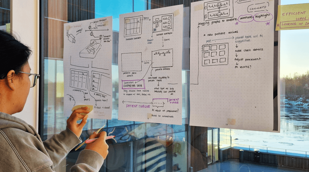Paper sketches of patient-monitoring interfaces displayed for discussion.