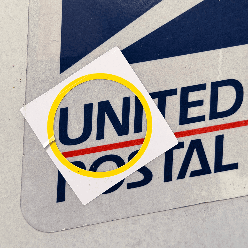 A square UNI sticker pasted over larger street lettering.