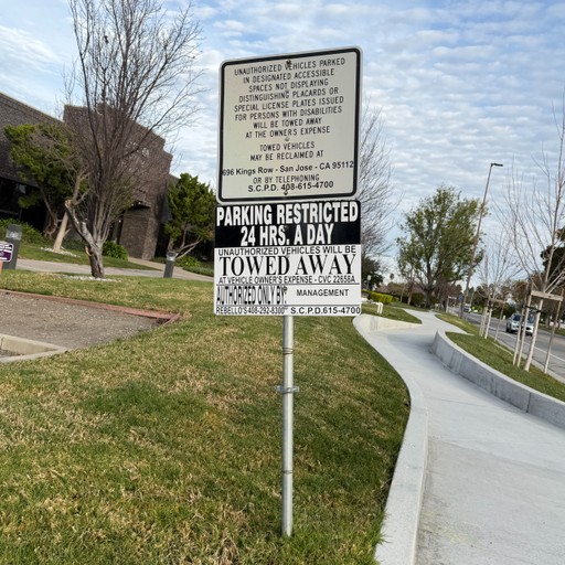 Parking-restriction sign beside a road and grass verge.