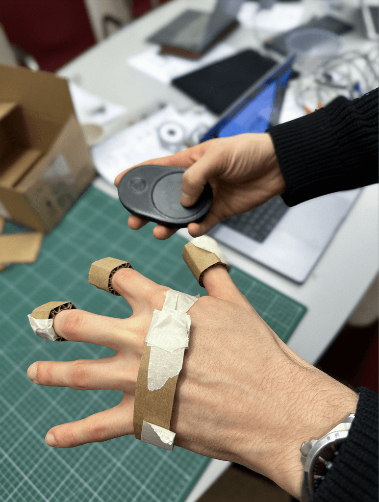 A participant testing finger-mounted sensors and a handheld recorder prototype.