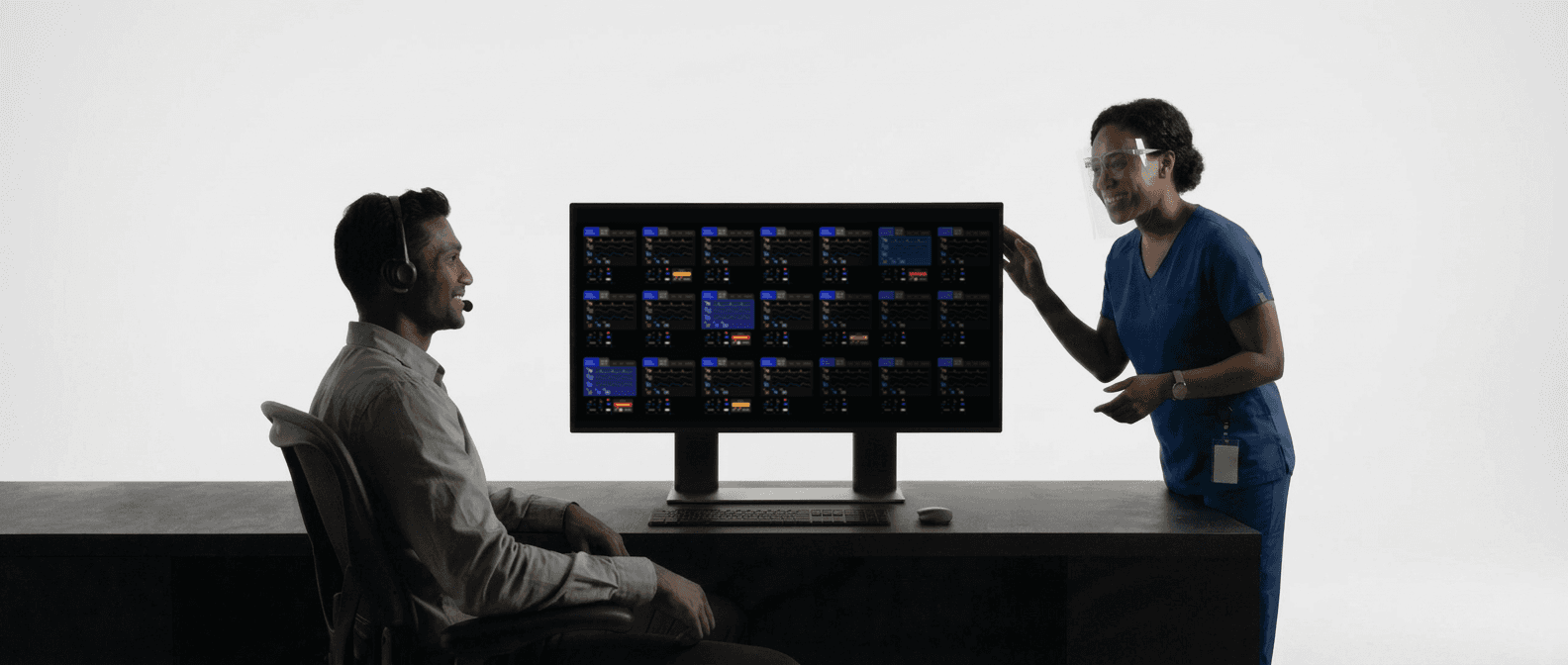 A telehealth nurse and colleague reviewing a patient monitoring screen.